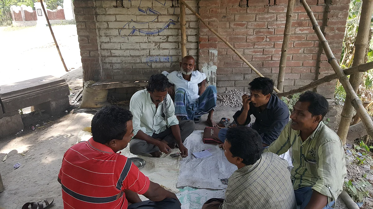Karim Sheikh watching his friends play a card game, in Plassey, Nadia. (Photo: Chandan Nandy/ <b>The Quint</b>)