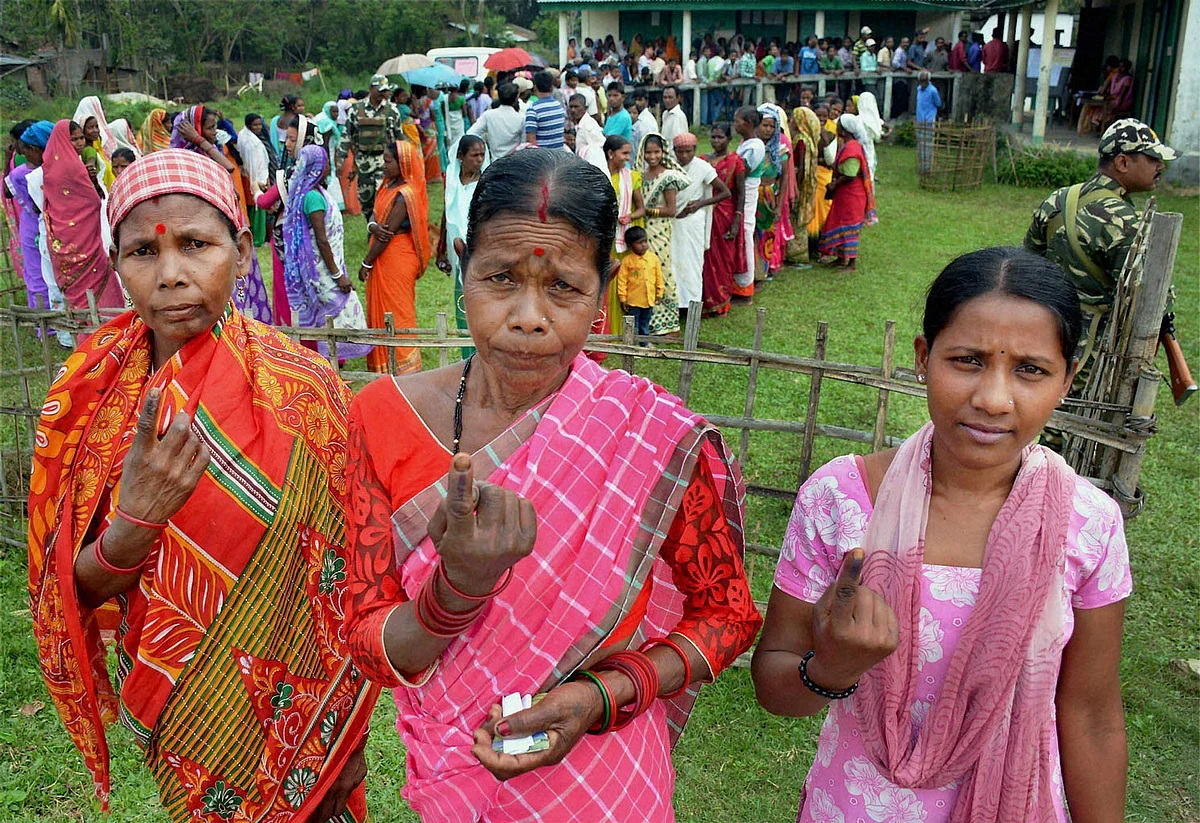 Tea tribe women showing their inked fingers after casting their vote during the first phase Assembly Elections for Duliajan Assembly Constituency at Bordubi. (Photo: PTI) 