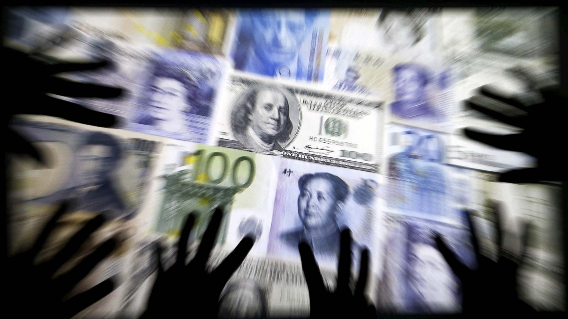 Hands are silhouetted against a backdrop projected with the picture of various currencies of money in this illustration taken on 4 April 2016. (Photo: Reuters) 