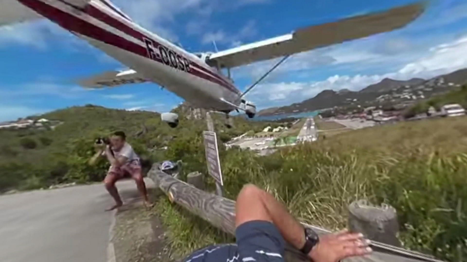 This lucky tourist had a narrow escape when a plane skimmed the top of his head while taking a photo in St Barts. (Photo: AP/Caters News screengrab)