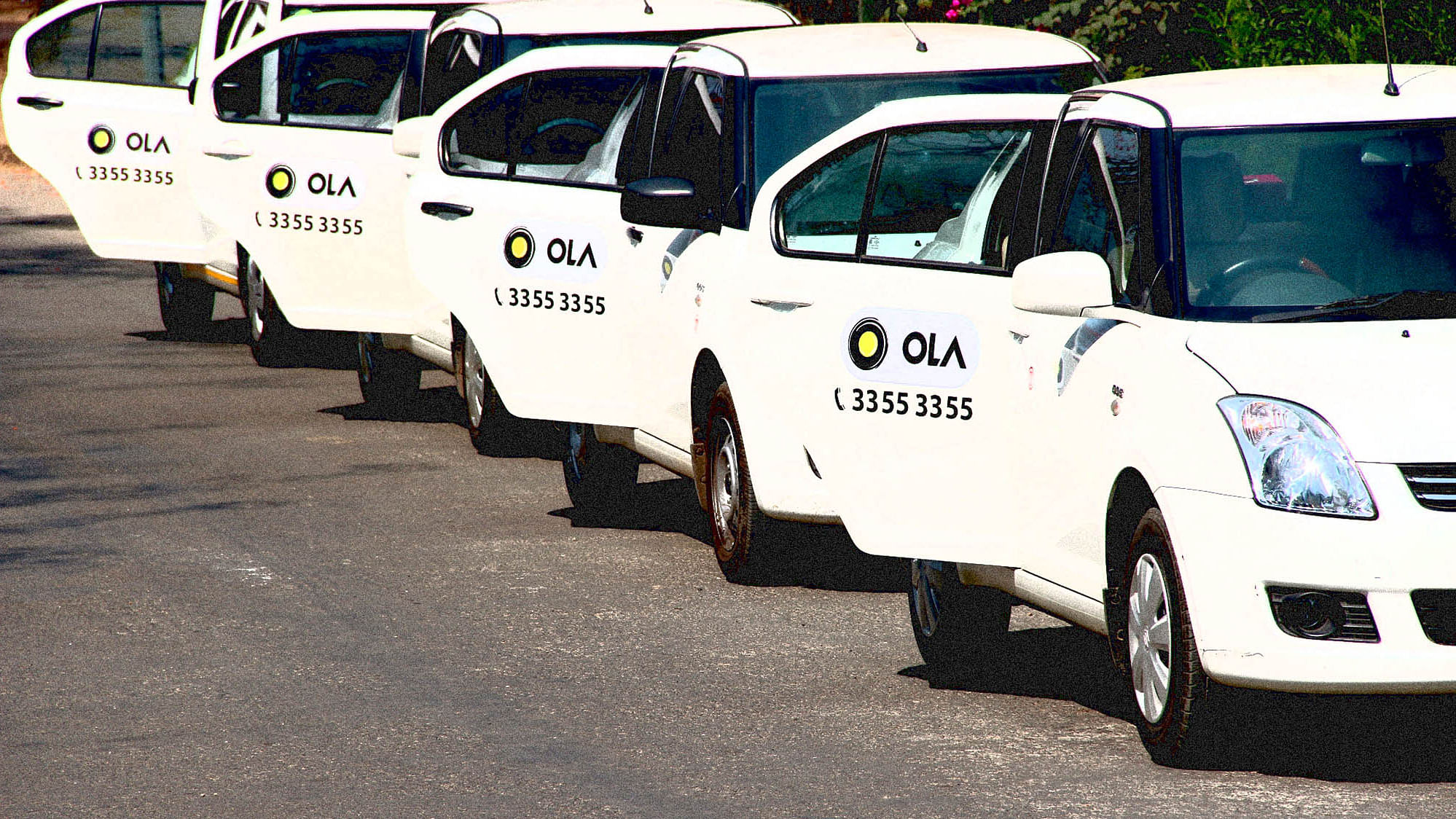 A fleet of Ola cabs wait on the roadside in Mumbai.&nbsp;
