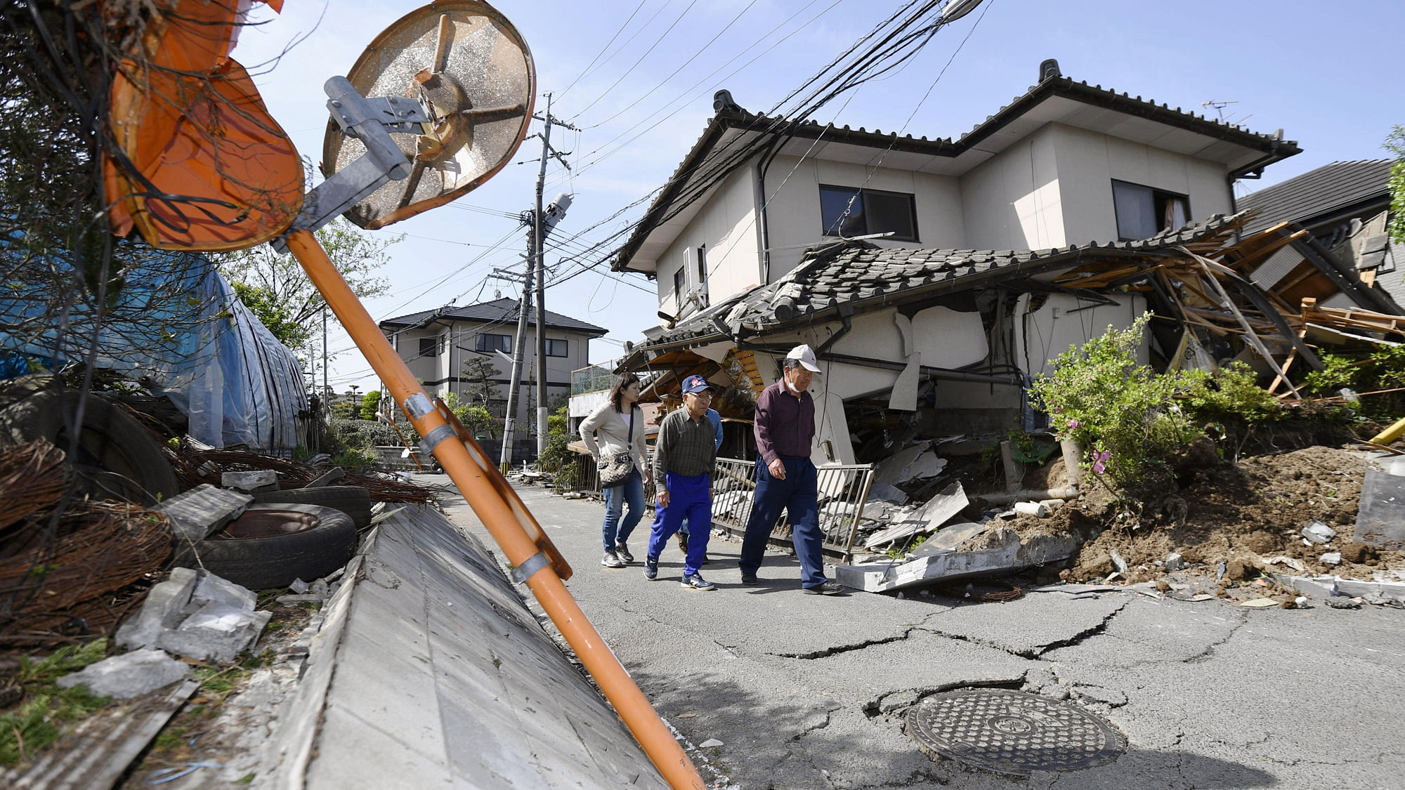 Residents walk past a house damaged by a magnitude-6.5 earthquake in Mashiki, Kumamoto prefecture, southern Japan, on Friday, 15 April 2016. (Photo: AP)