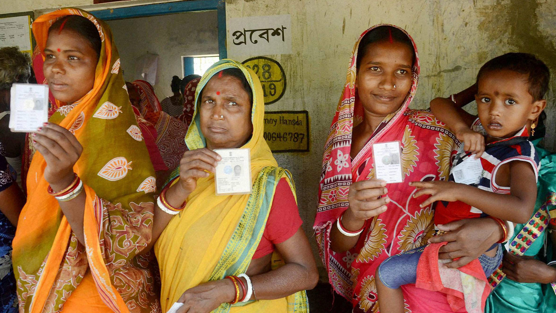 Women show  their voter cards before casting votes at a polling booth during the state assembly elections in Kharagpur. (Photo: PTI)