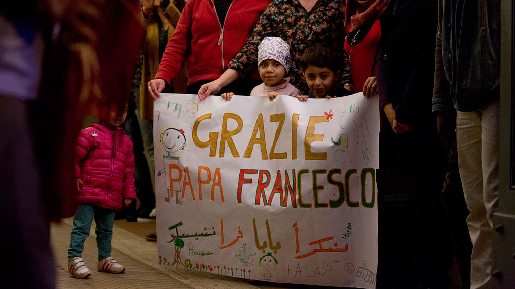 Kids hold up a  banner with writing in Italian reading “Thank you Pope Francis” as they welcome a group of 12 Syrian refugees in Rome. (Photo: AP)
