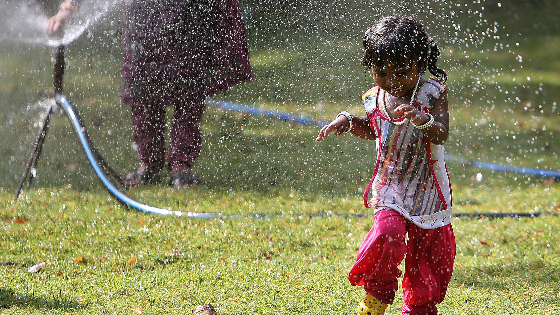 A child plays in front of a water sprinkler to cool off on a hot summer day. (Photo: AP)