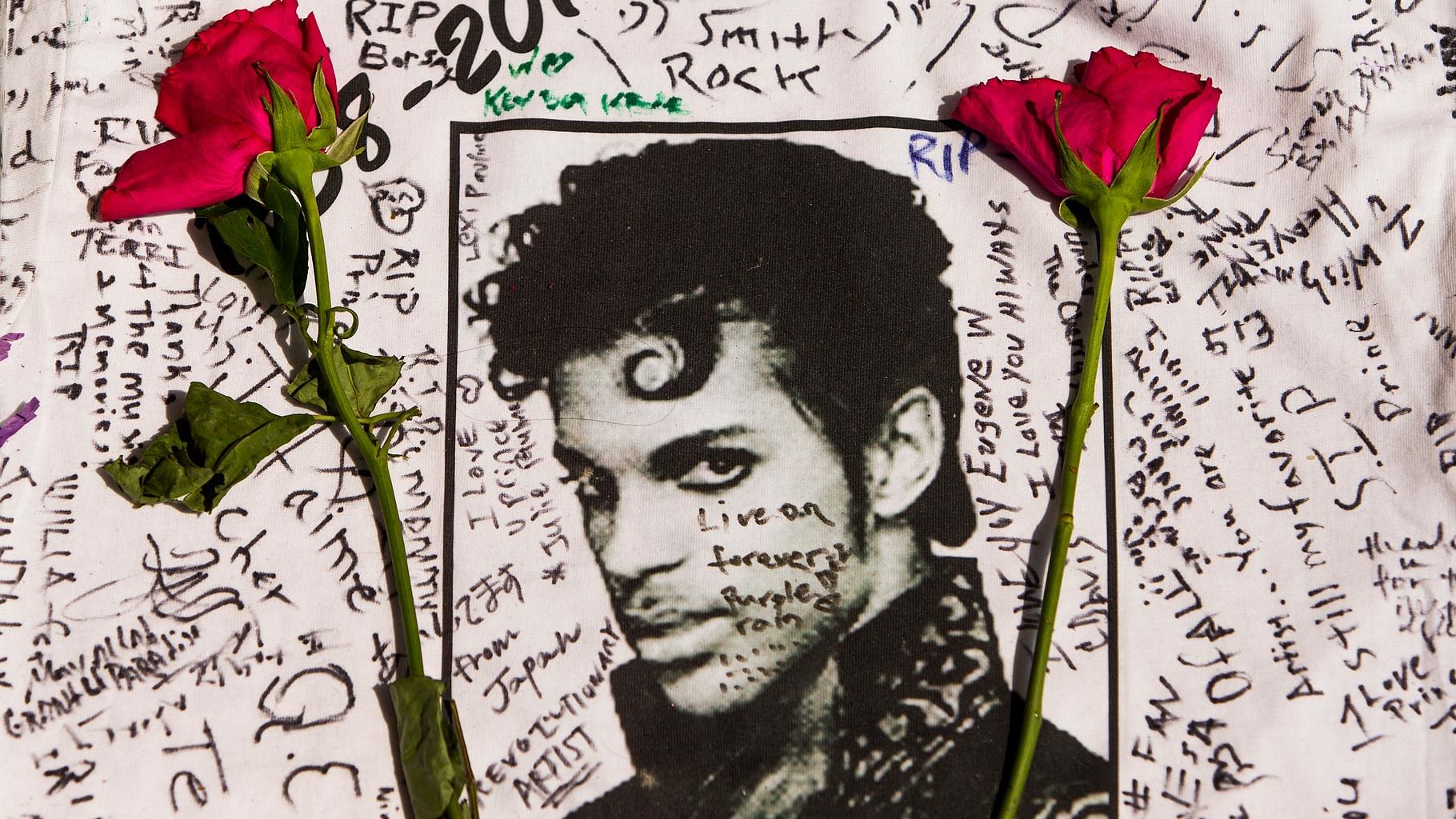 Flowers lay on a T-shirt signed by fans of singer Prince at a makeshift memorial place created outside Apollo Theater in New York. (Photo: AP)
