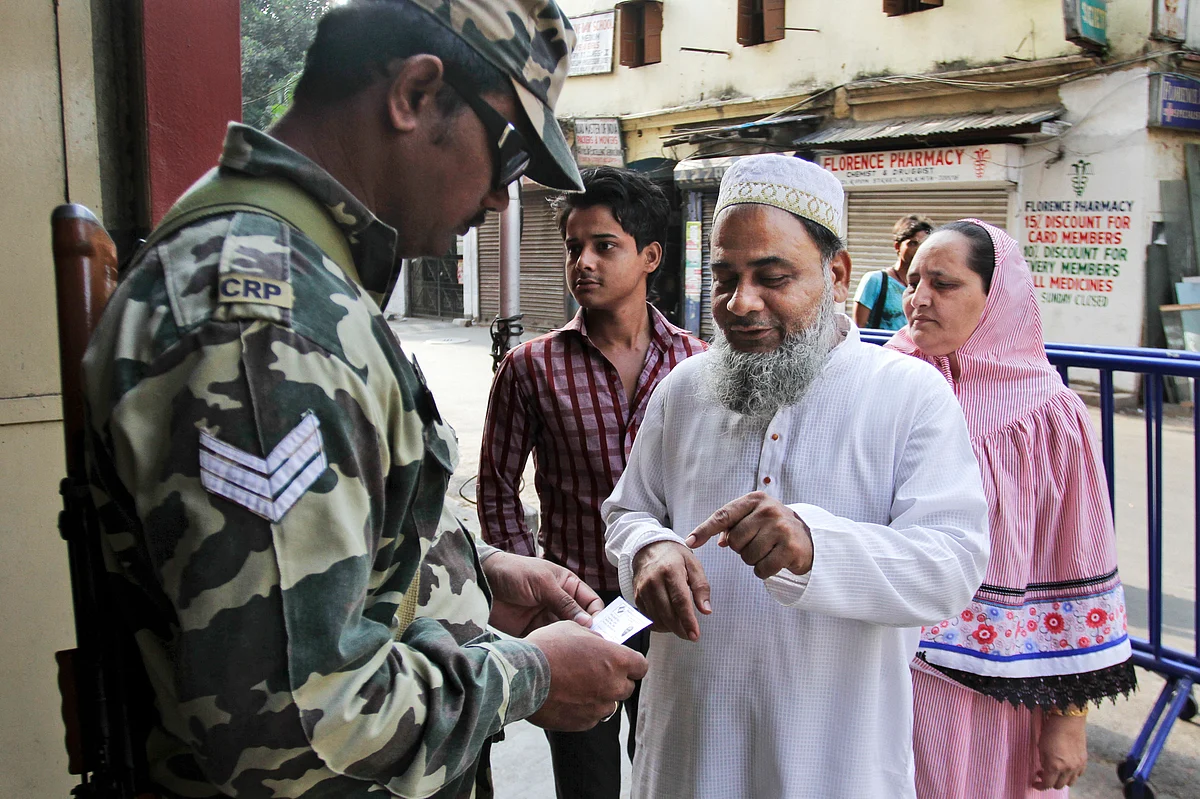 An Indian paramilitary soldier checks the identity of voters outside a polling booth during the third phase of voting in the West Bengal state Assembly elections. (Photo: AP)