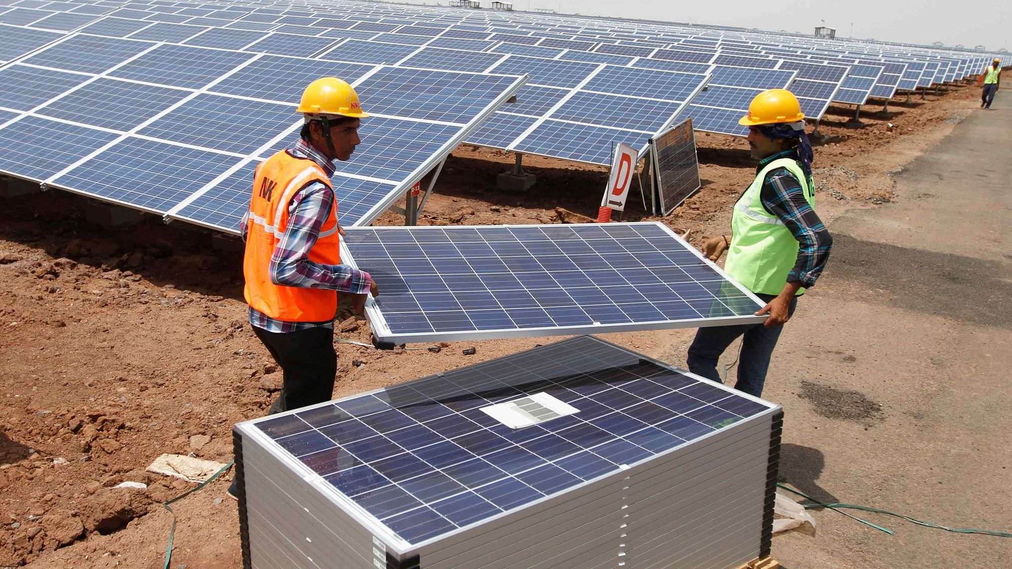 Workers carry photovoltaic solar panels for installation at the Gujarat solar park. (Photo: Reuters)