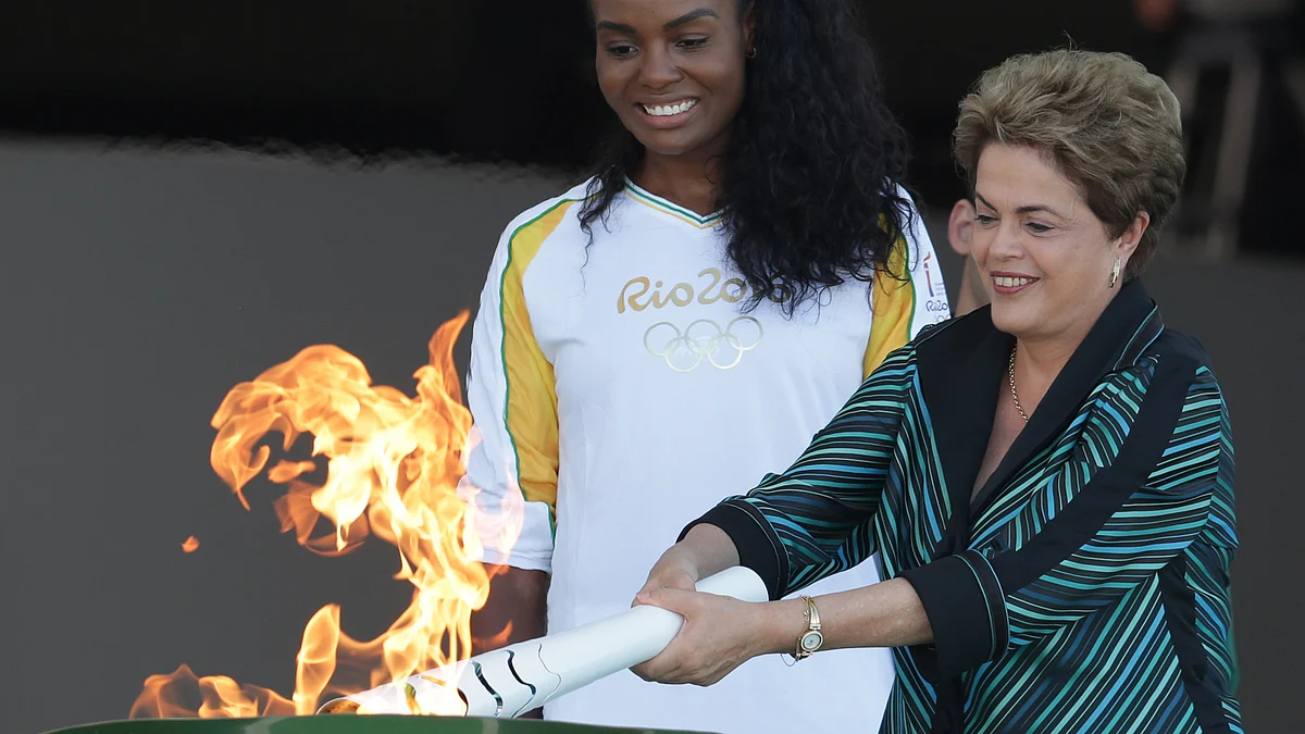 Brazil’s President Dilma Rousseff lights the Olympic flame as Brazilian volleyball player Fabiana Claudino looks on. (Photo: AP)