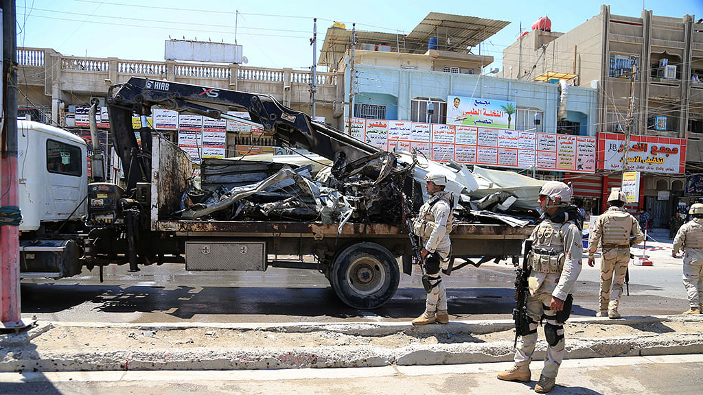 

Iraqi security forces stand near the site of a bomb attack in Baghdad northern Shaab district, Iraq. (Photo: AP)