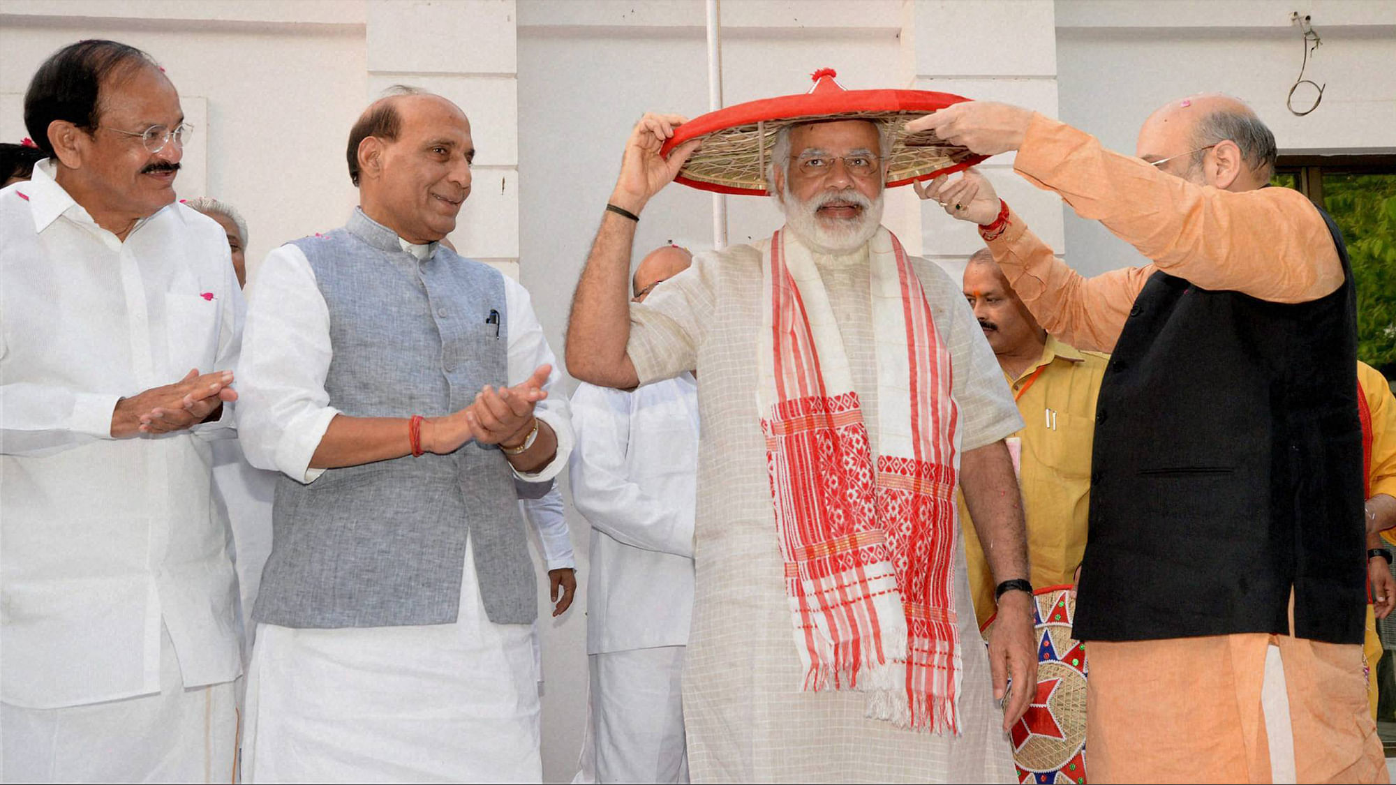 BJP President Amit Shah presents an Assamese japi and Gamocha to Prime Minister Narendra Modi on his arrival at the party office in New Delhi on Thursday for a meeting after Assembly poll results. (Photo: PTI)