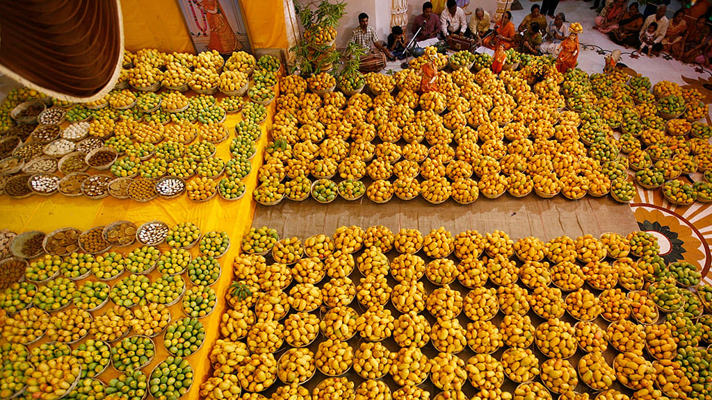 

Hindu devotees sing religious songs next to baskets of mangoes kept as offerings for the Hindu God Lord Krishna inside a temple during mango festival in Ahmedabad. (Photo: Reuters)