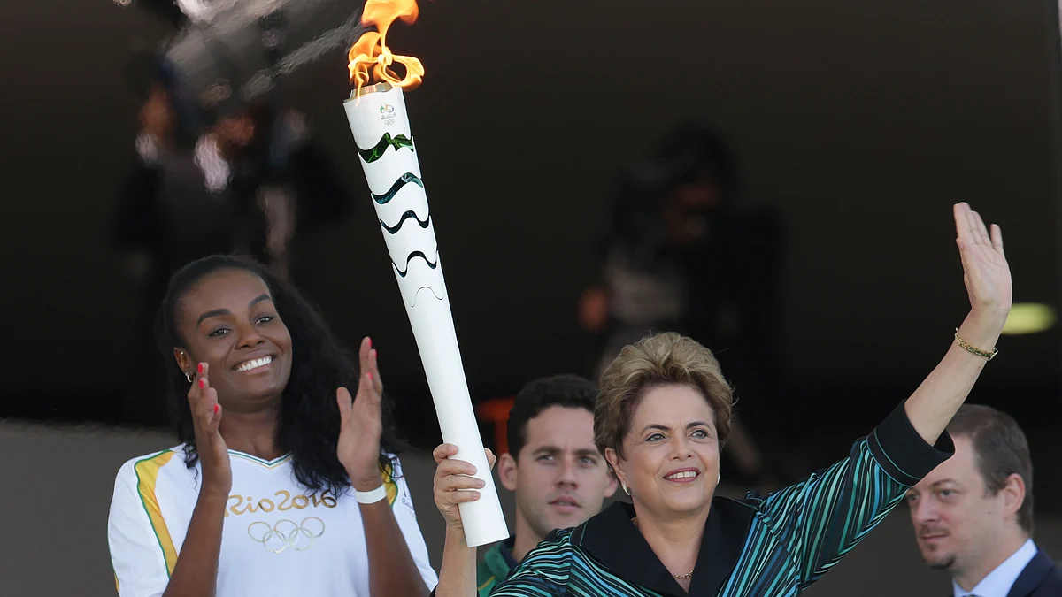 Brazil’s President Dilma Rousseff holds the Olympic torch as Brazilian volleyball player Fabiana Claudino applauds after the torch was ignited at Planalto presidential palace in Brasilia (Photo: AP)