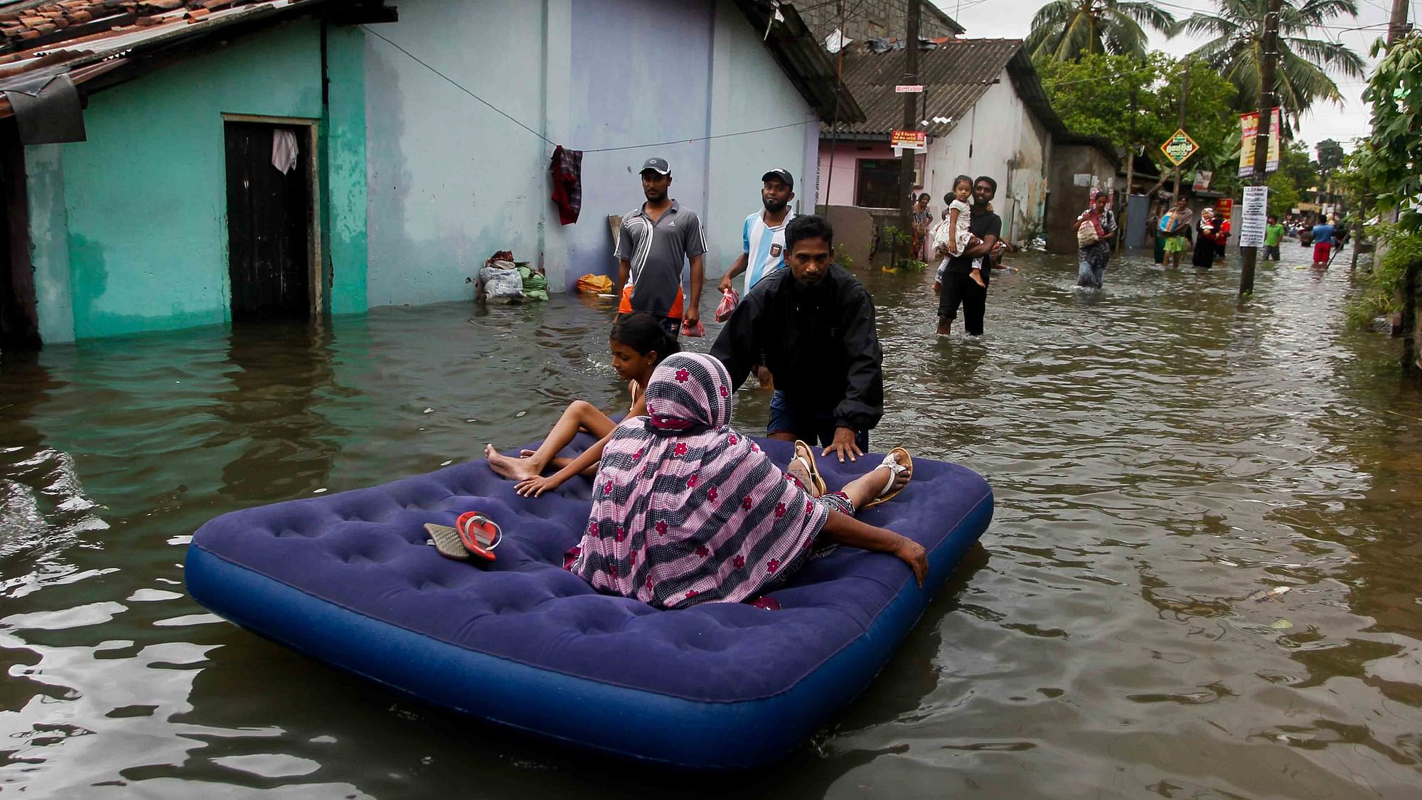 An elderly woman and girl being shifted on a mattress in flood-hit Colombo. (Photo: AP)