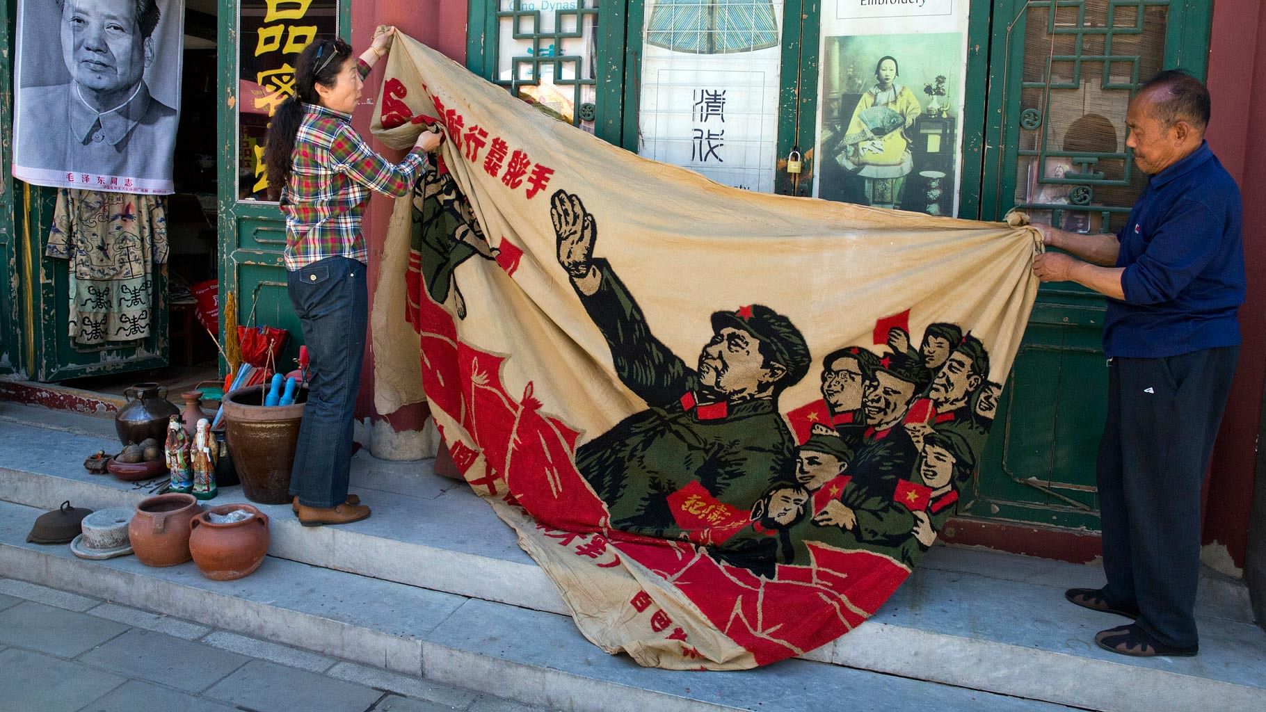 Vendors unfurl a banner from 1969 depicting former Chinese leader Mao Zedong as he “inspects the great army of the Cultural Revolution”. (Photo: AP)
