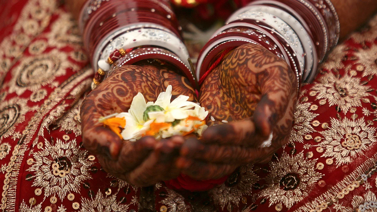 A bride holds flowers with <i>mehendi</i> on her hands during her wedding ceremony. (Photo: Reuters)