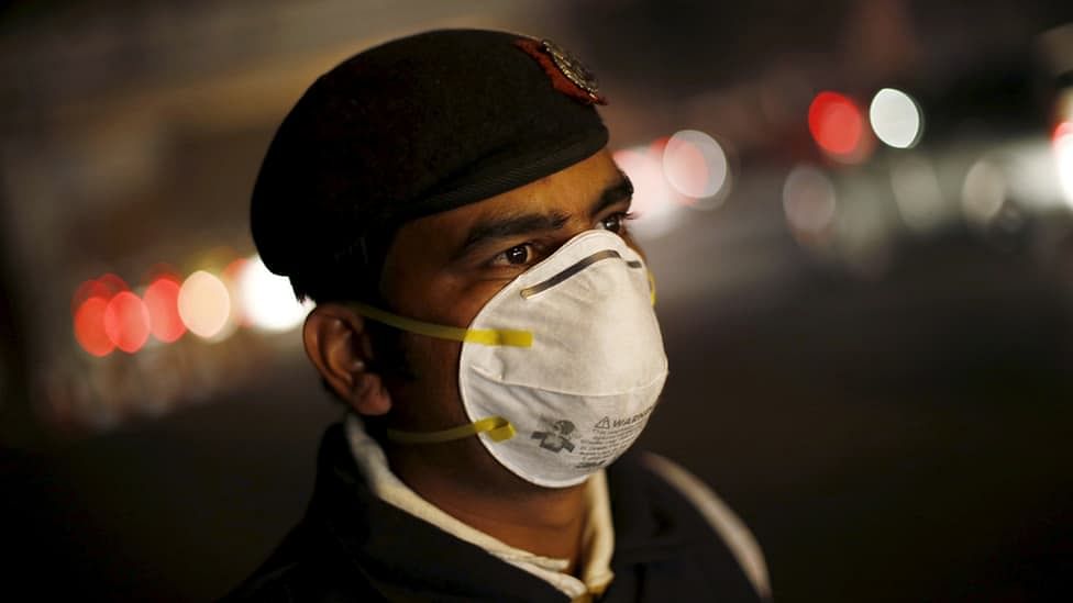 A traffic policeman wears a mask to protect himself from dust and air pollution as he stands on a road-divider in New Delhi, 23 December  2015. (Photo: Reuters)