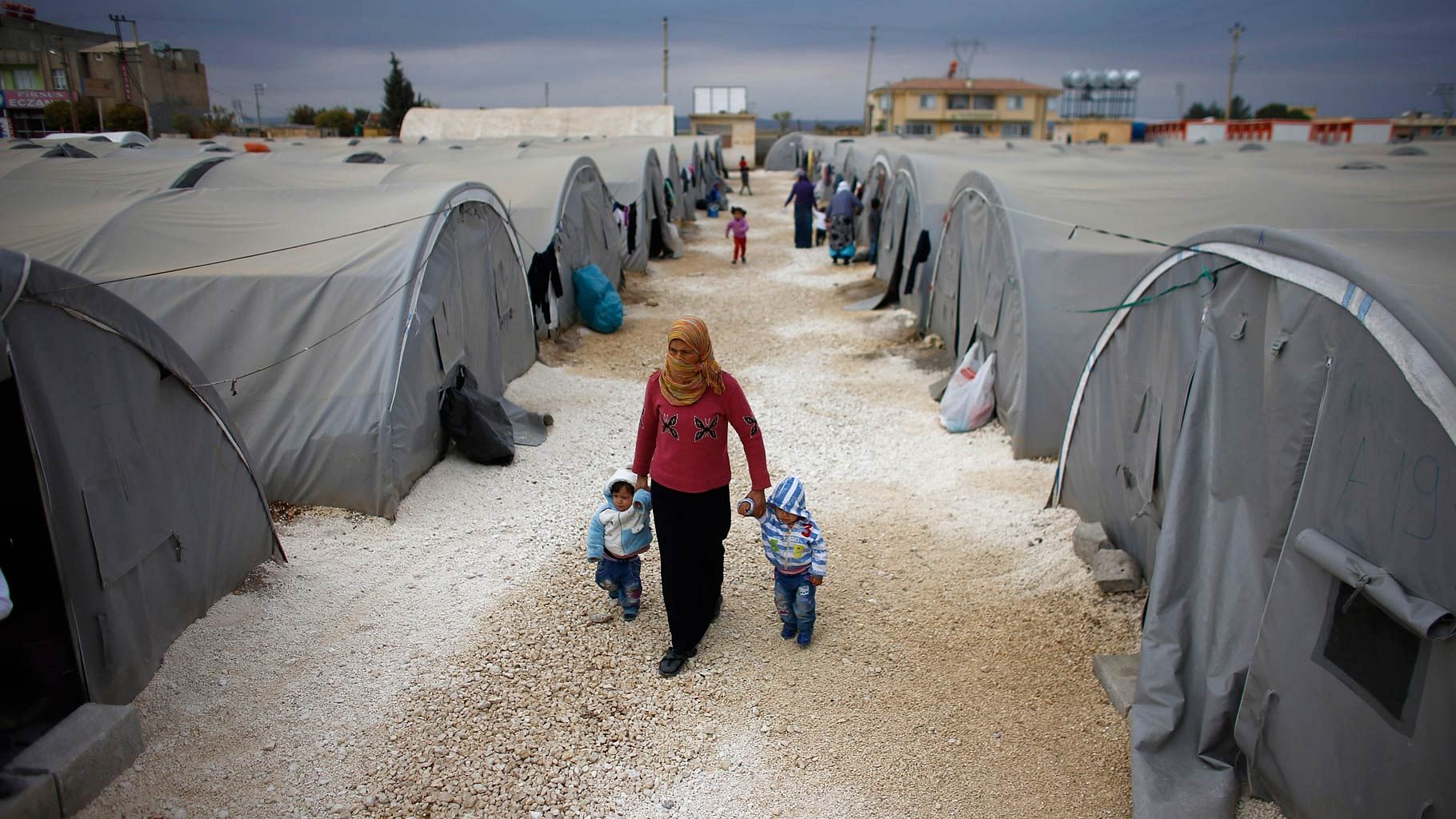 A Kurdish refugee woman from the Syrian town of Kobani walks with her children at a refugee camp in the border town of Suruc, Sanliurfa province. (Photo: Reuters)