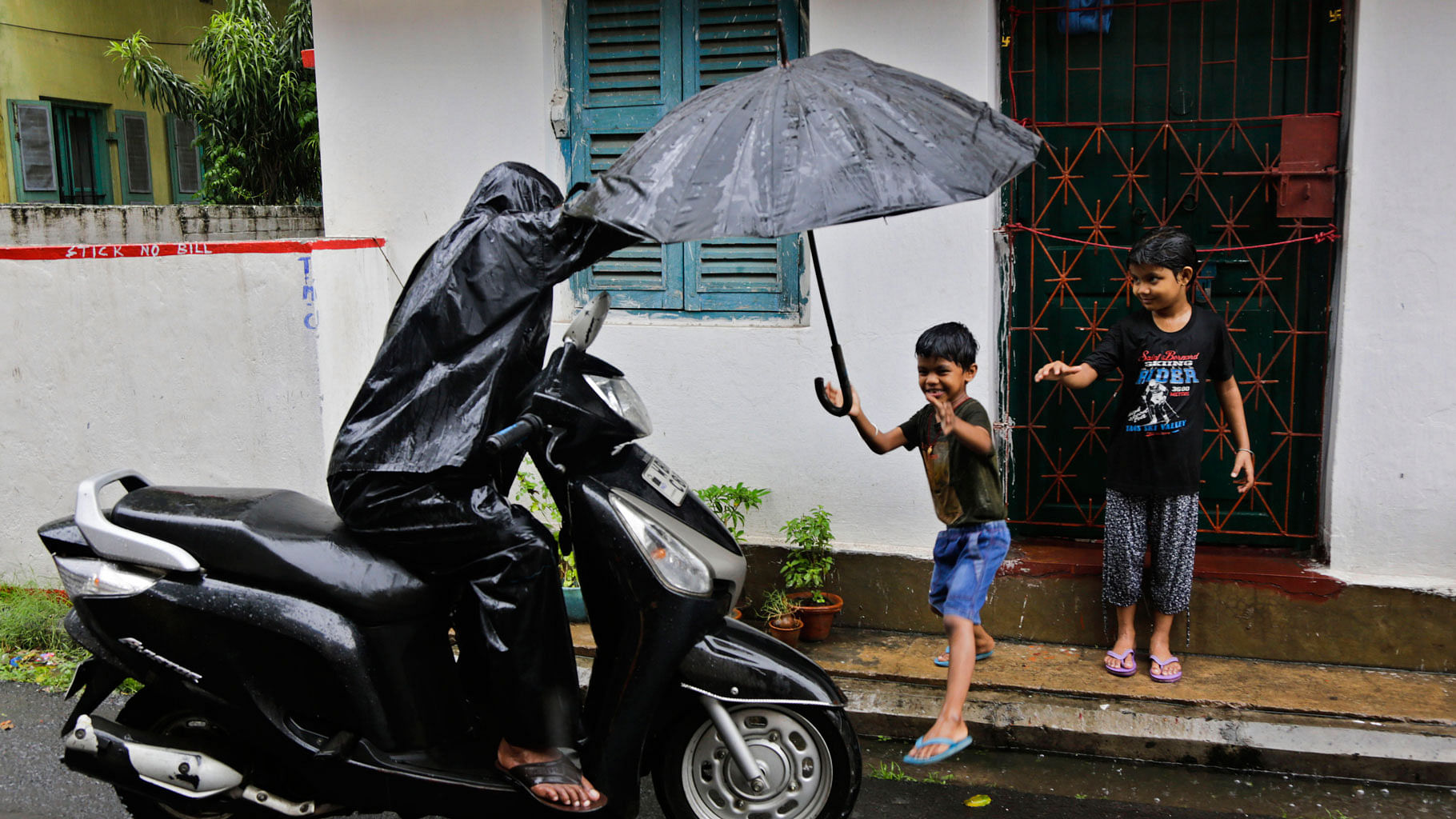A child reaches to his father for an umbrella as it rains in Kolkata. ( Photo: AP)<a></a>