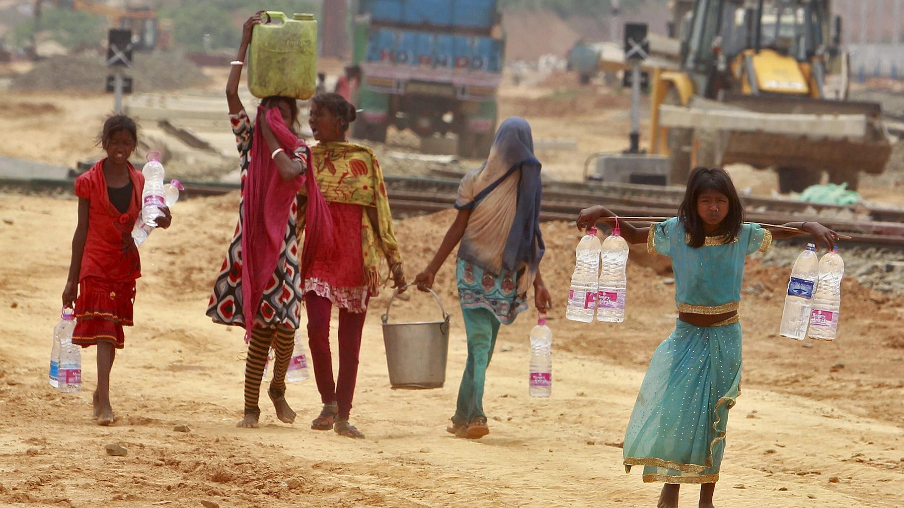 Young girls carry containers filled with drinking water beside the railway station in Agartala. (Photo: Reuters)&nbsp;