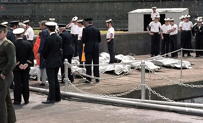 Officers, Irish sailors, and rescue workers look on as the 329 victims of the Air India jet are lined up on the docks in Cork, Ireland on 24 June 1985. 