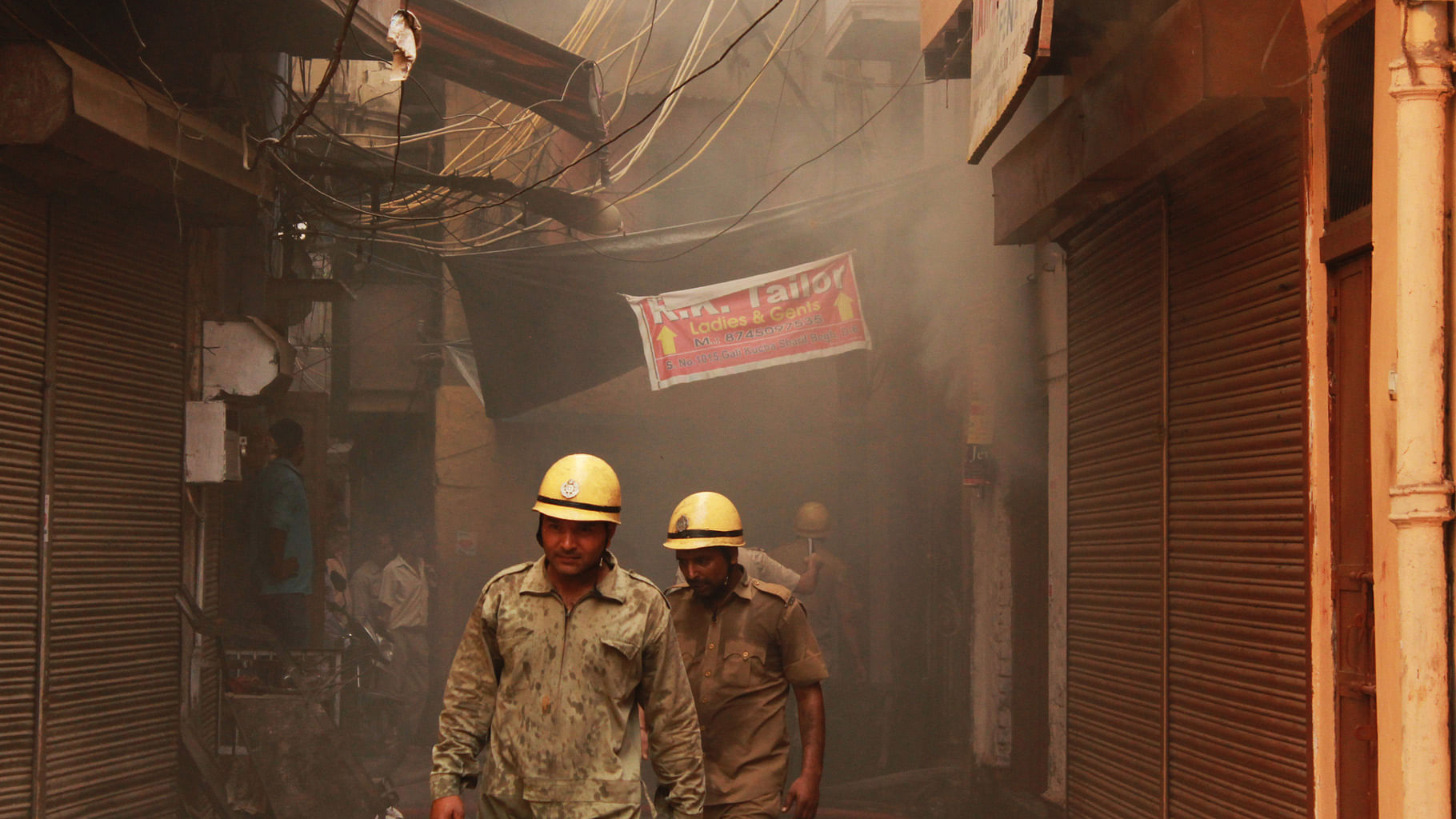 Fire-fighters under a smoking building in Chawri Bazar.