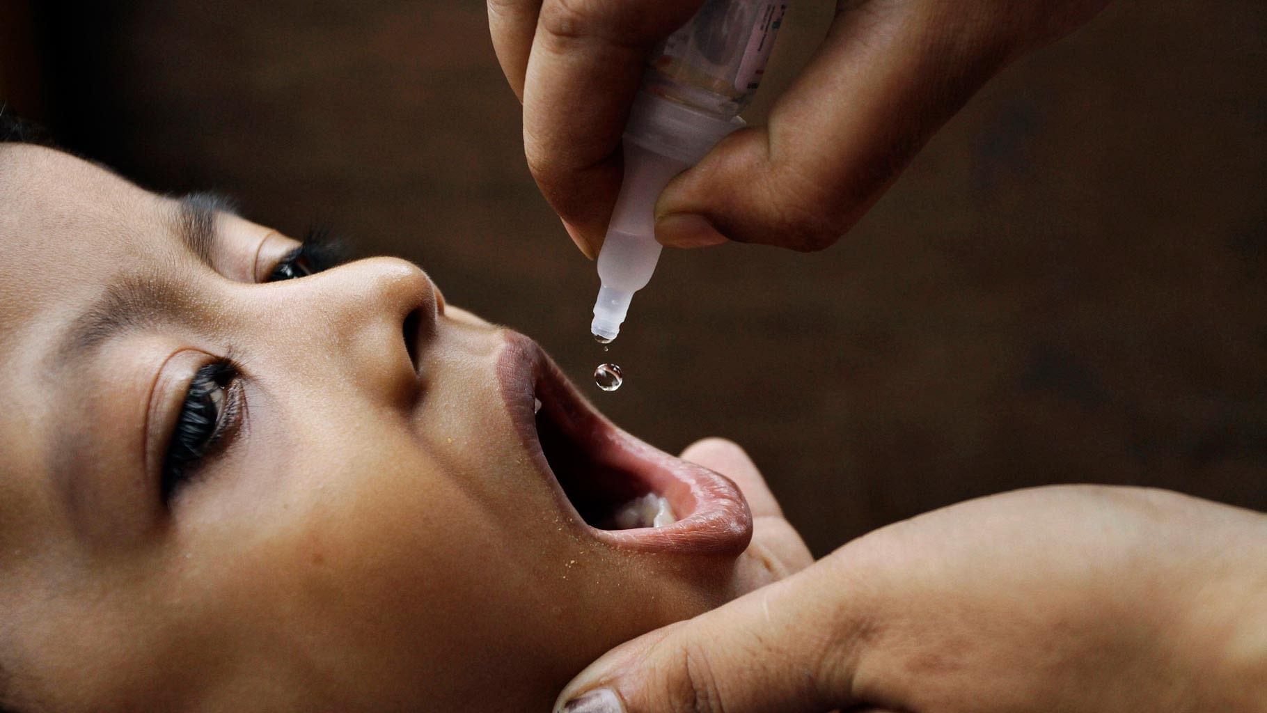 A health worker administers a polio vaccine drop to an infant in India.&nbsp;