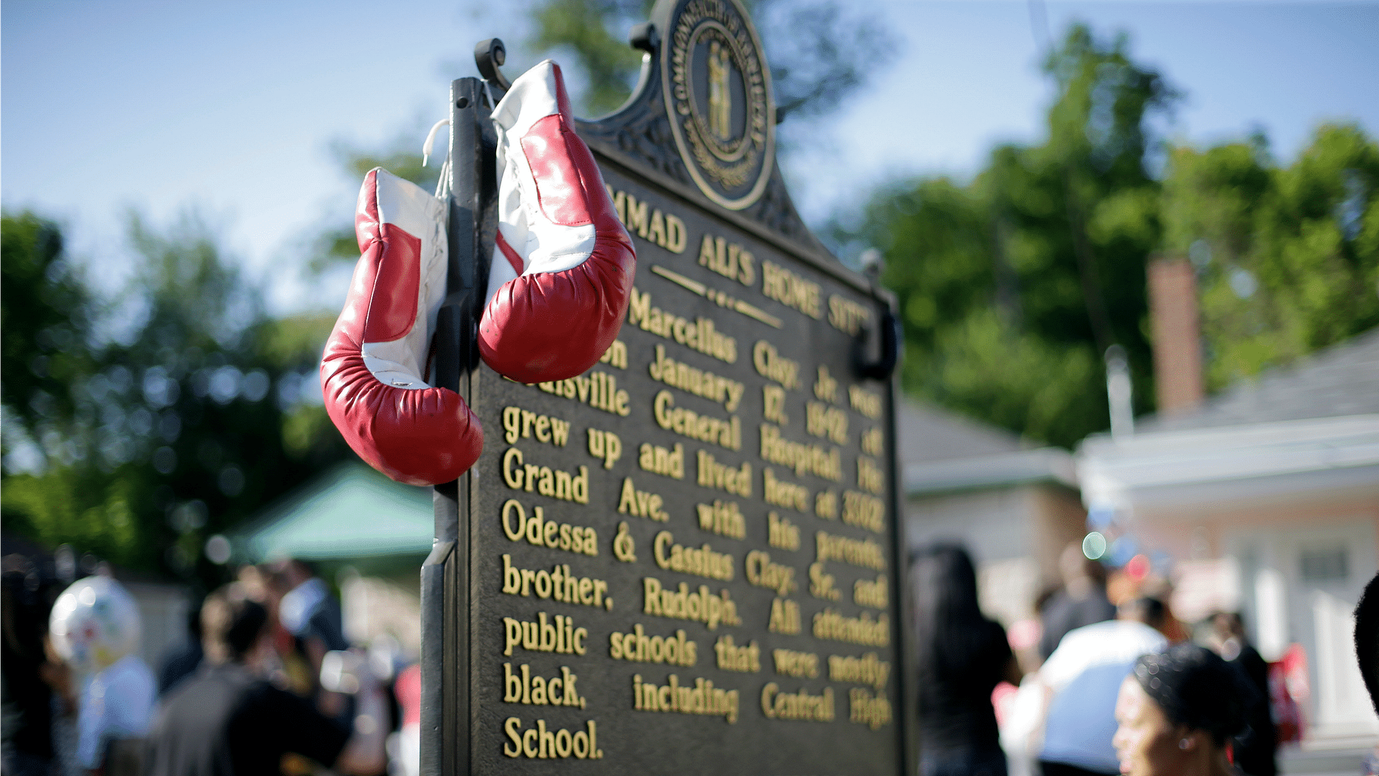 

Boxing gloves hang on the historic site plaque in front of the boyhood home of Muhammad Ali as people wait for the arrival of his funeral procession Friday, June 10, 2016, in Louisville, Ky. (Photo: AP)