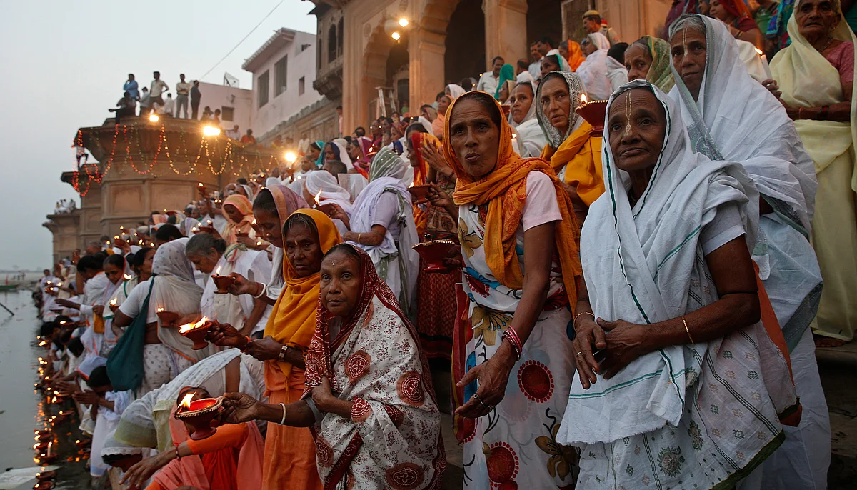 Widows, who have been abandoned by their families, hold earthen oil lamps as they offer prayers on the banks of Yamuna. (Photo: Reuters)