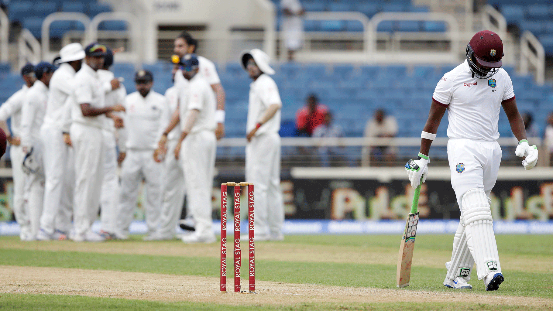 West Indian batsman Darren Bravo walks back to the pavilion as team India celebrates. (Photo: AP)