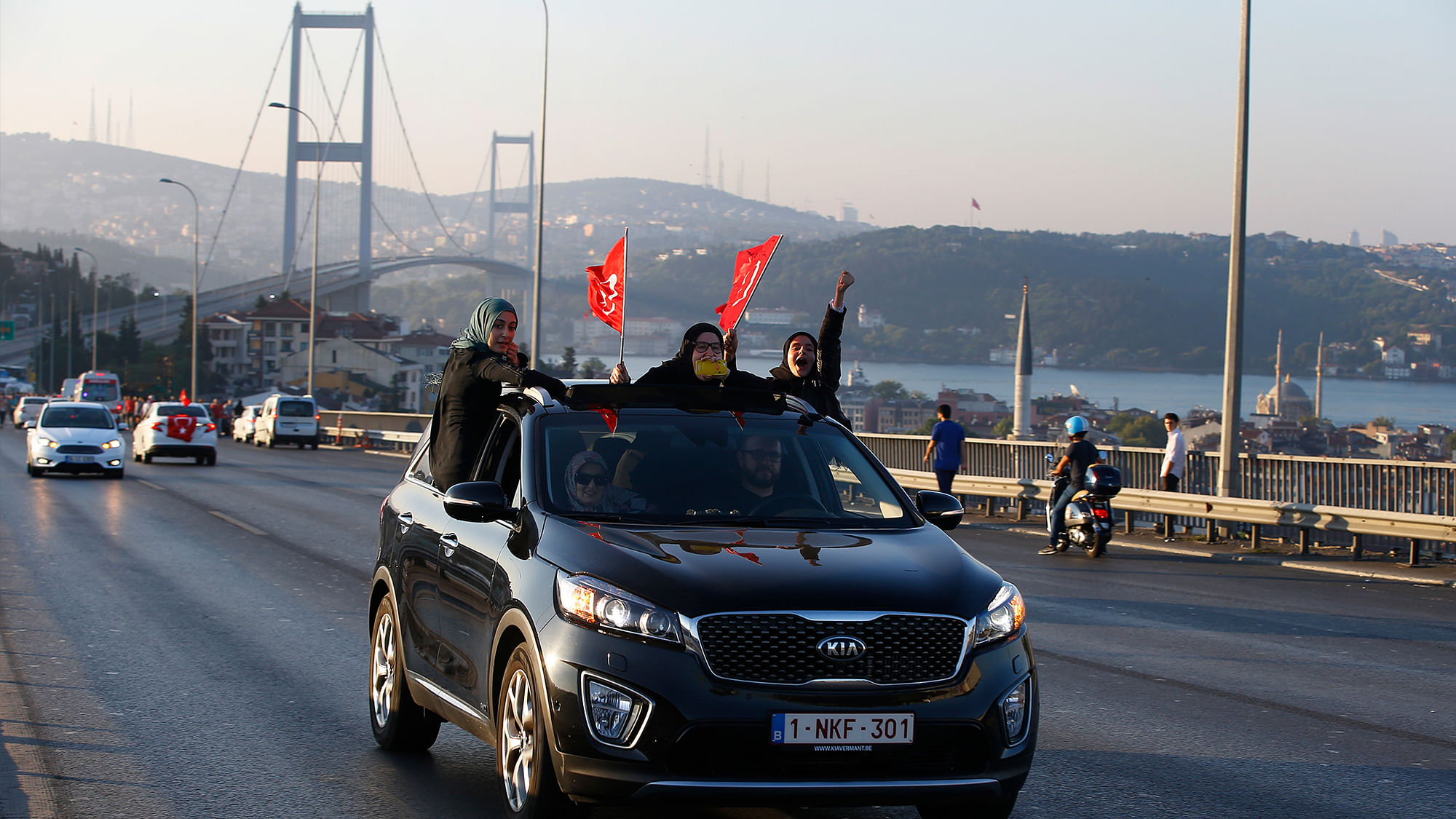 Turkish people holding flags are driven in a car, backdropped by Istanbul’s iconic Bosporus Bridge on Saturday after Friday’s failed military coup attempt. (Photo: AP)
