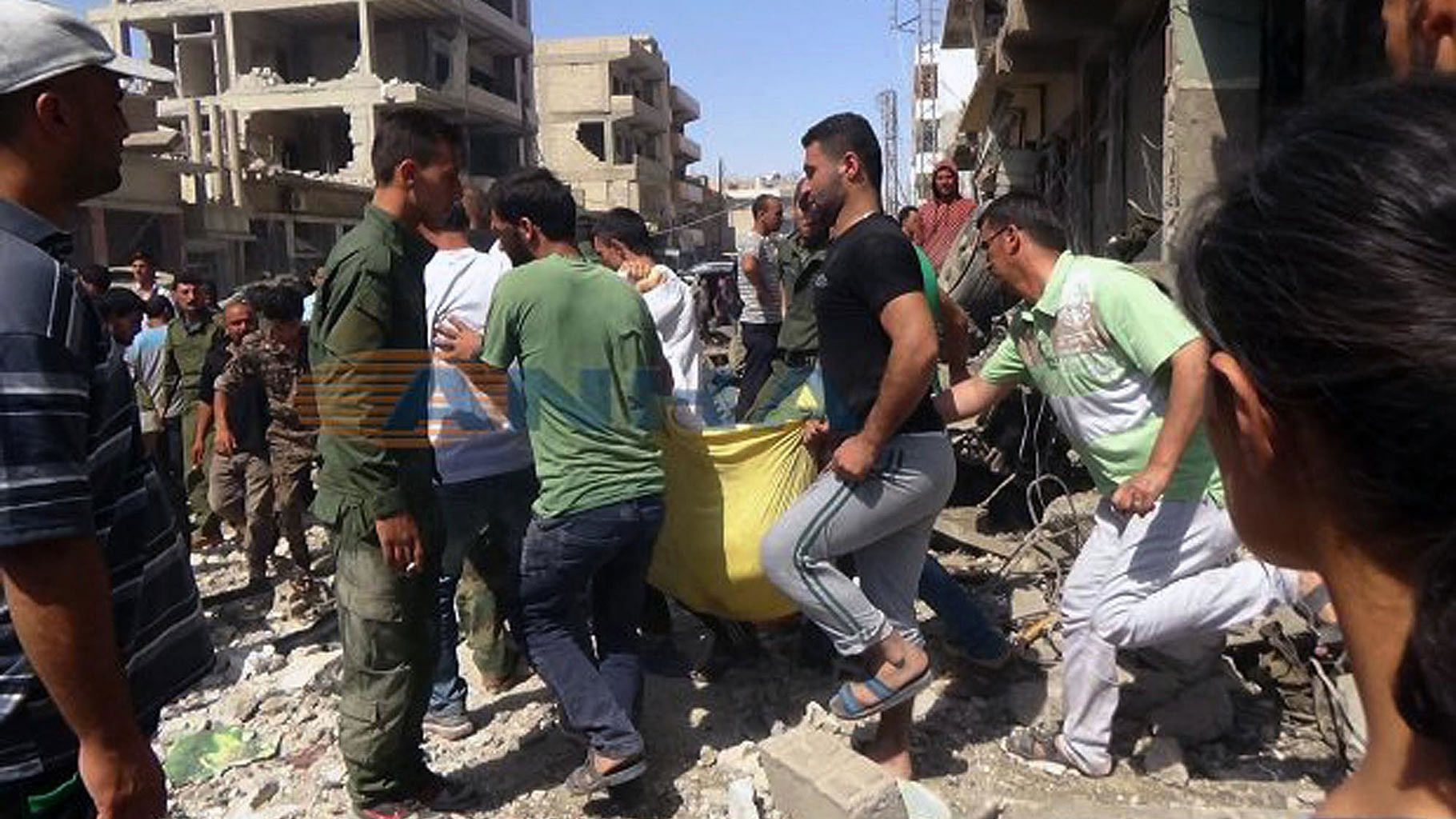 Syrians carry a victim after twin bombings struck Kurdish town of Qamishli, Syria, Wednesday on July 27. (Photo: AP)