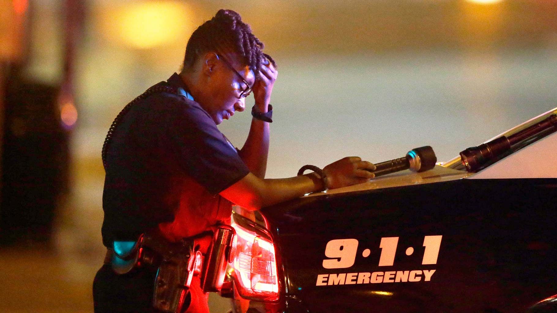 A Dallas police officer, who did not want to be identified, takes a moment as she guards an intersection in the early morning after a shooting in downtown Dallas, Friday, 8 July 2016. (Photo: AP)