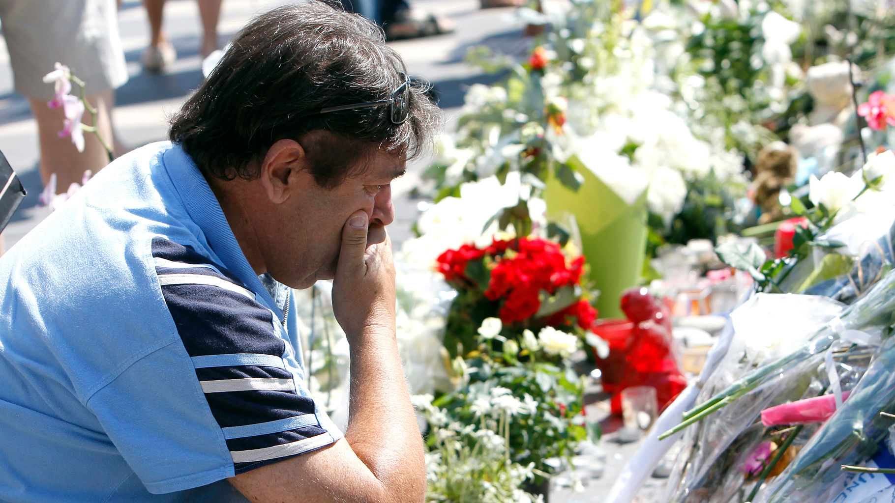 A man mourns as he looks at the flowers placed at a new memorial in a gazebo in a seaside park of the Promenade des Anglais in Nice. (Photo: AP)