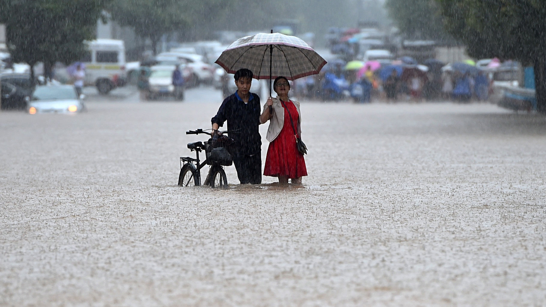 A couple holding an umbrella wade through a flooded road in Wuhan in central China’s Hubei province. (Photo: AP)