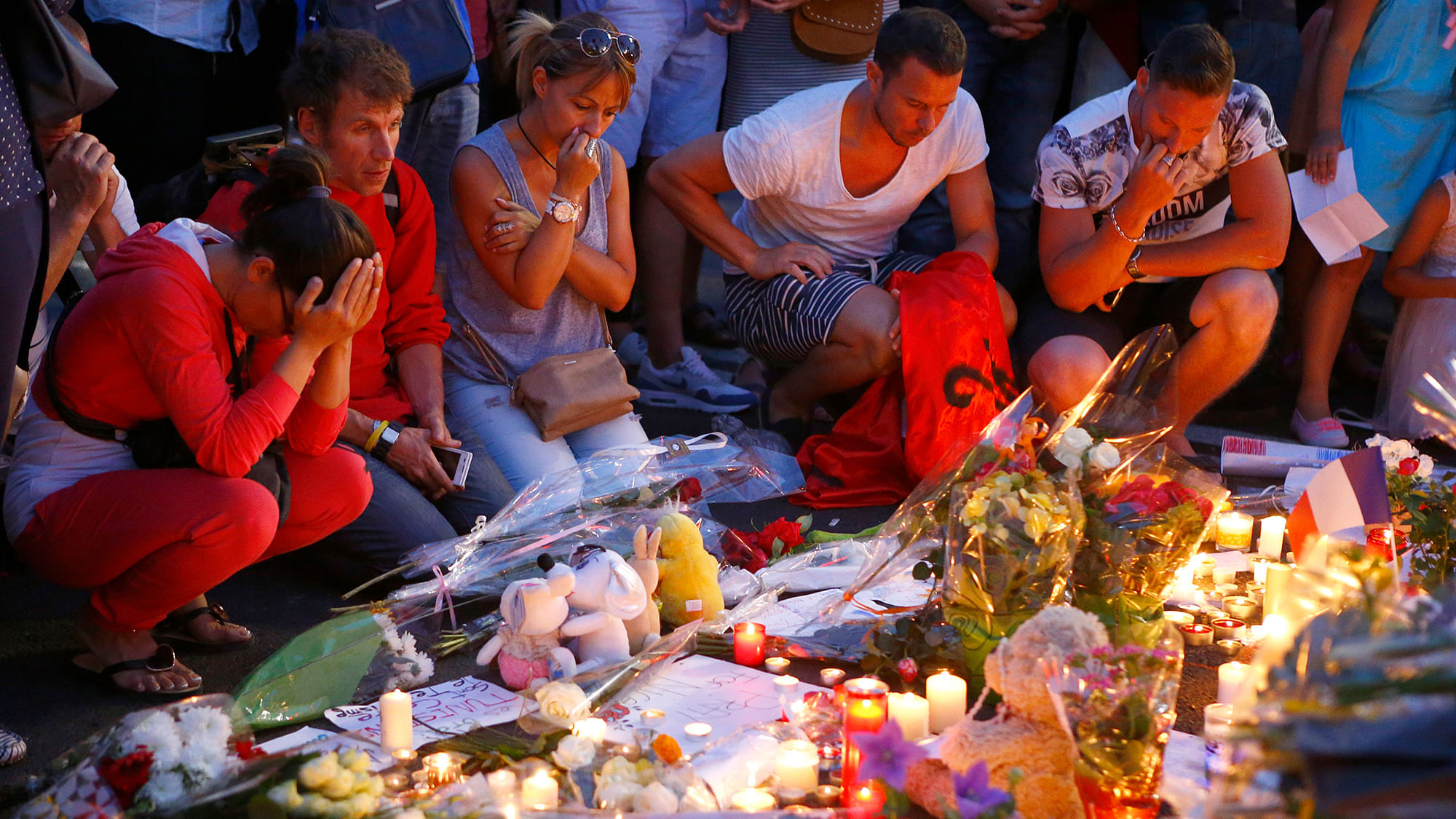 People pay homage to the victims of a truck attack at a makeshift memorial near the area where a truck mowed through revelers in Nice, southern France on Friday. (Photo: AP)
