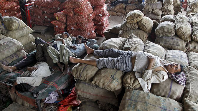 Vendors take a nap on stacked sacks of vegetables at a wholesale market on a hot summer day in Chandigarh, India, 29 May 2015. (Photo: Reuters)
