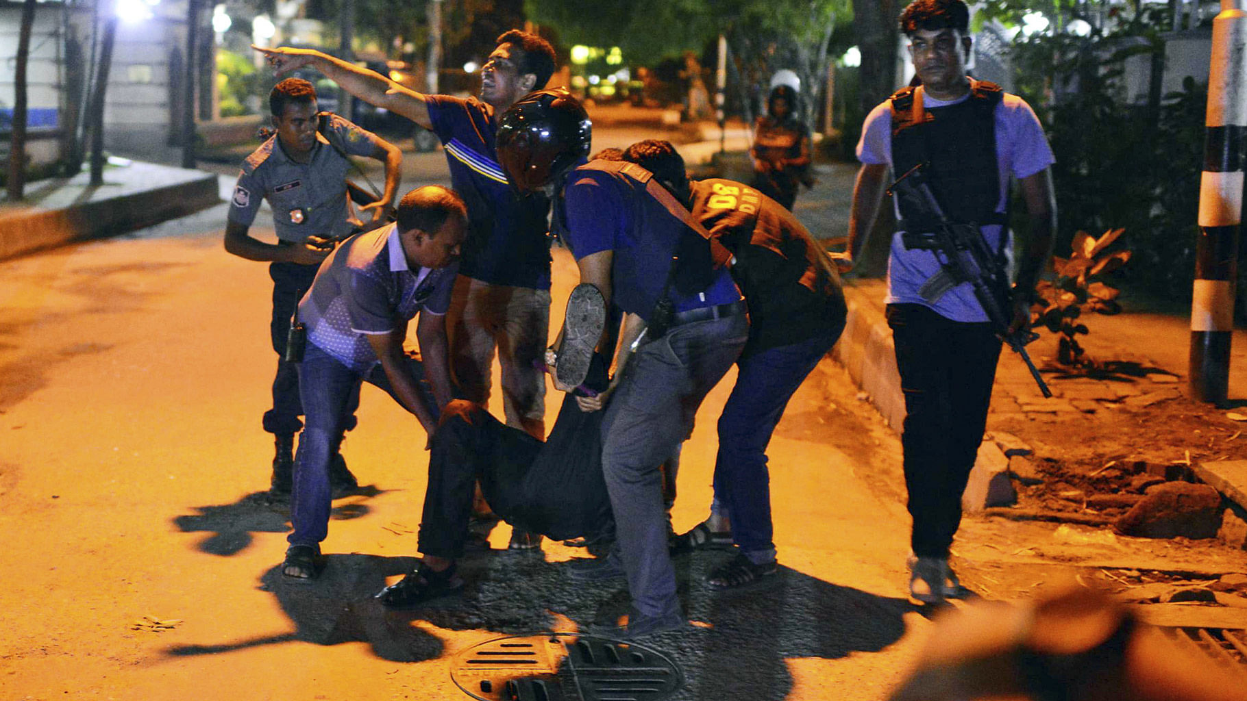 People help an unidentified injured person after a group of armed gunmen attacked a restaurant in Dhaka (Photo: AP)