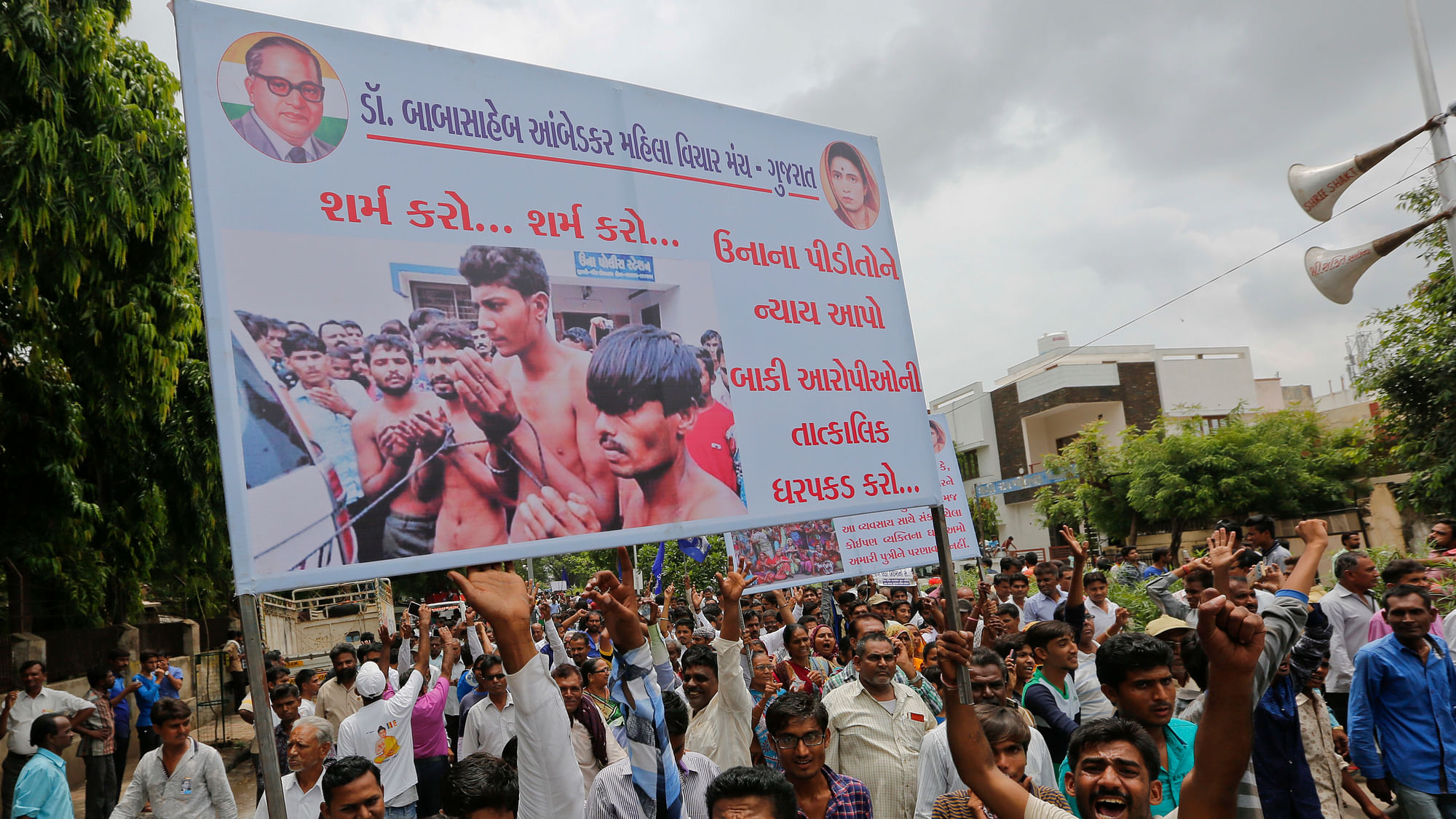 Members of India’s low-caste Dalit community hold a banner as they gather for a rally to protest against the attack on their community members in Ahmadabad, India, Sunday, July 31, 2016.Dalits have been protesting after four men belonging to their community (shown in photograph in the banner) were beaten while trying to skin a dead cow in Una in western Gujarat state early this month. The banner in Gujarati reads “shame shame, Give justice to Una victims, immediately arrest rest accused”. (Photo: AP)