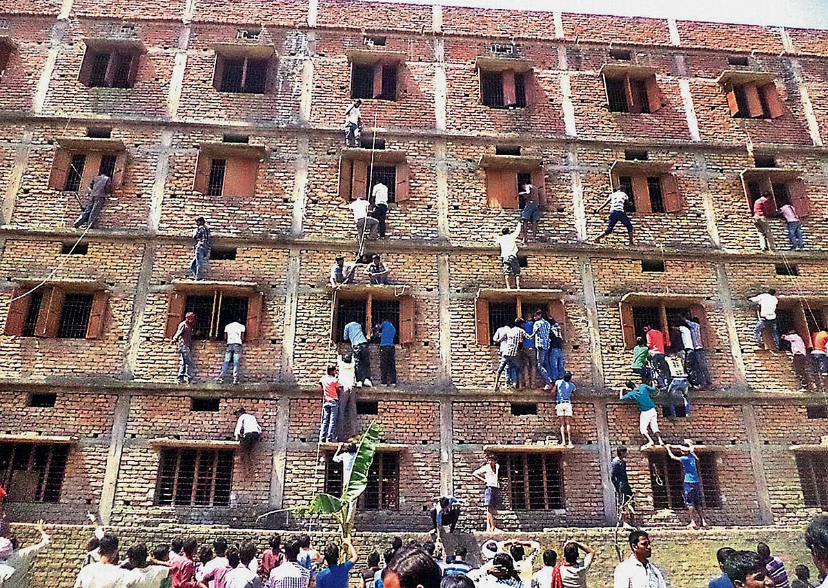In this March 18, 2015 photo, family members climb the wall of a building to help students appearing in an examination in Hajipur, Bihar. (Photo: AP)
