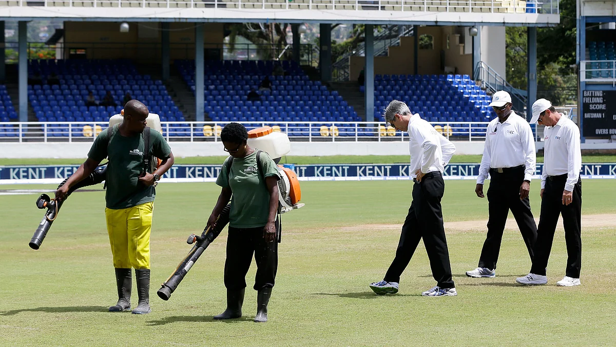 Umpires inspect the outfield as the ground staff dry the wet portion at Queen’s Park Oval during India vs West Indies 4th test match. (Photo: AP)