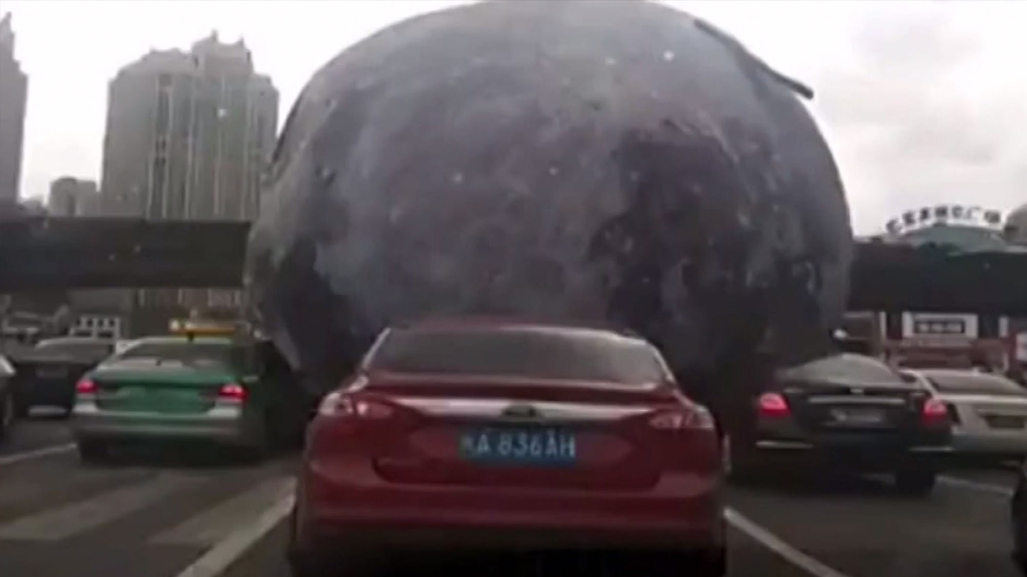 A giant moon balloon rolls down a busy motorway in China. (AP/Newsflare)