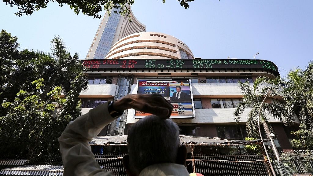 A man looks at a screen across the road displaying the Sensex on the facade of the Bombay Stock Exchange (BSE) building in Mumbai. (Photo: Reuters).