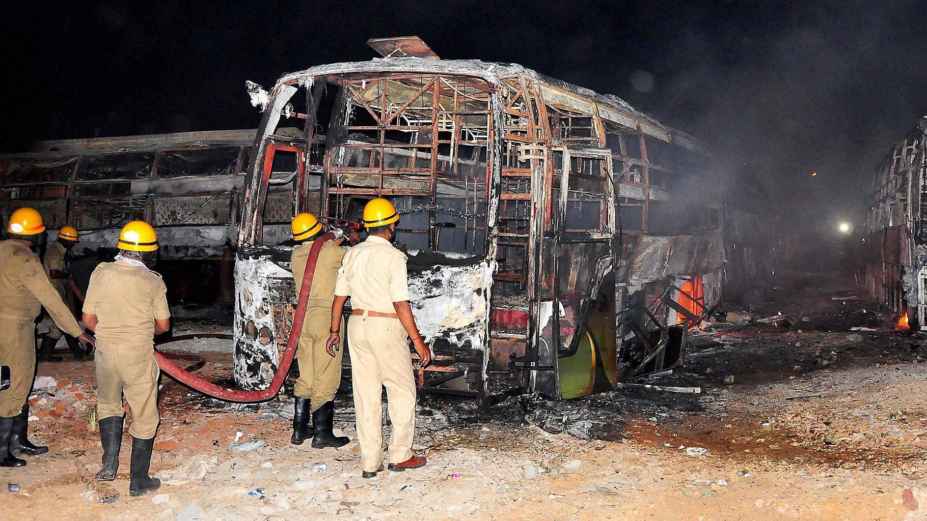 Firefighters trying to douse a fire in Tamil Nadu bound buses after they were torched by pro-Kannada activists during a protest over Cauvery water row, in Bengaluru on Monday. (Photo: PTI)