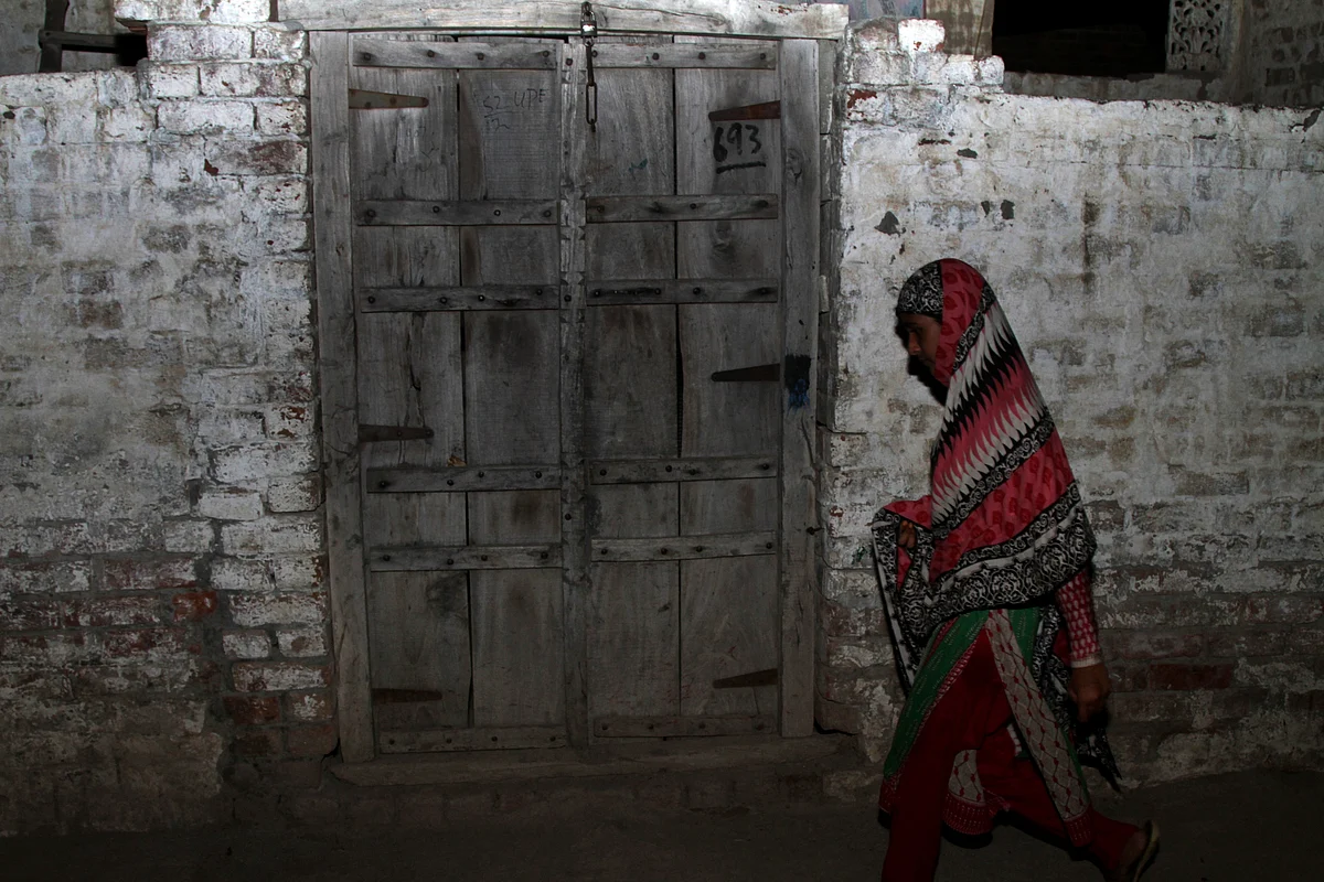 A Pakistani woman walks past the locked house of the boy in district Kasur, Pakistan. (Photo: AP)