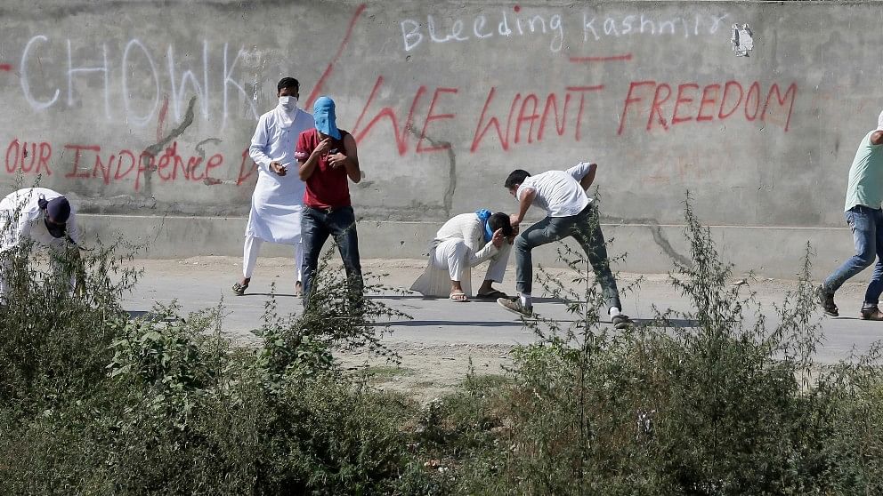 Kashmiri Muslim protesters duck to avoid pellets and tear gas fired on them by government forces in Srinagar. (Photo: AP)
