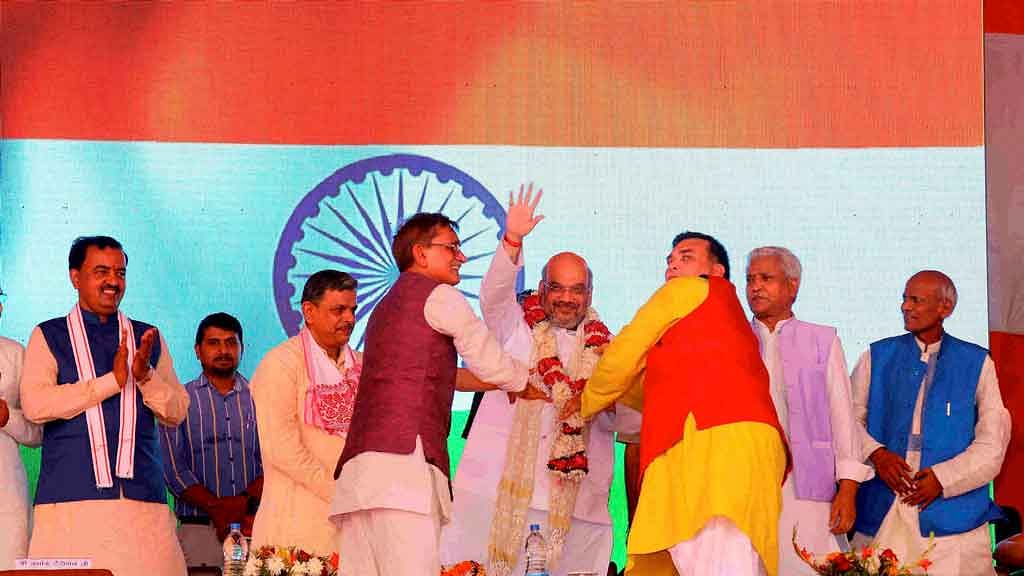 BJP National President Amit Shah is garlanded at a public meeting at Pt. Deen Dayal Dham in Farah, Mathura on Wednesday. (Photo Courtesy: PTI)&nbsp;