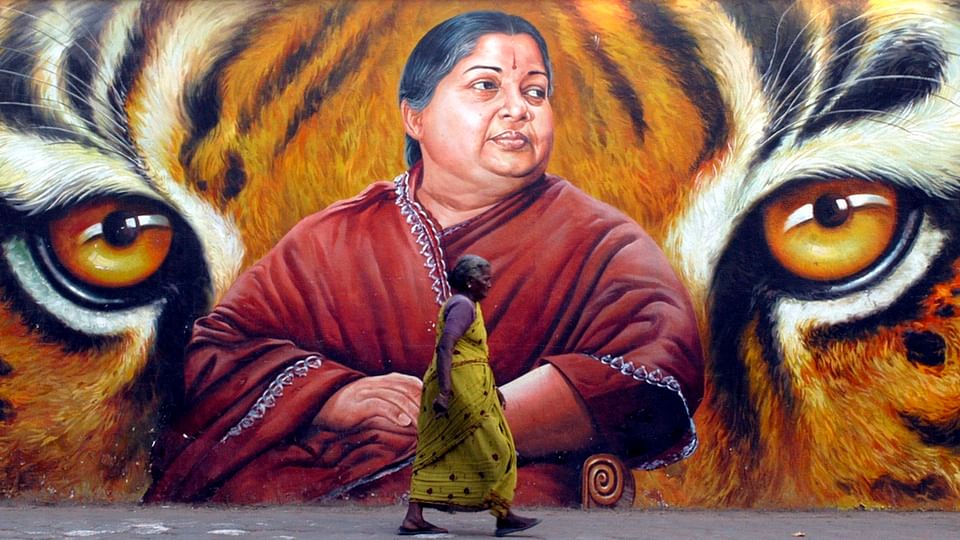 File photo of an old woman walking in front of a wall with Jayalalithaa’s painting on it. (Photo: Reuters)