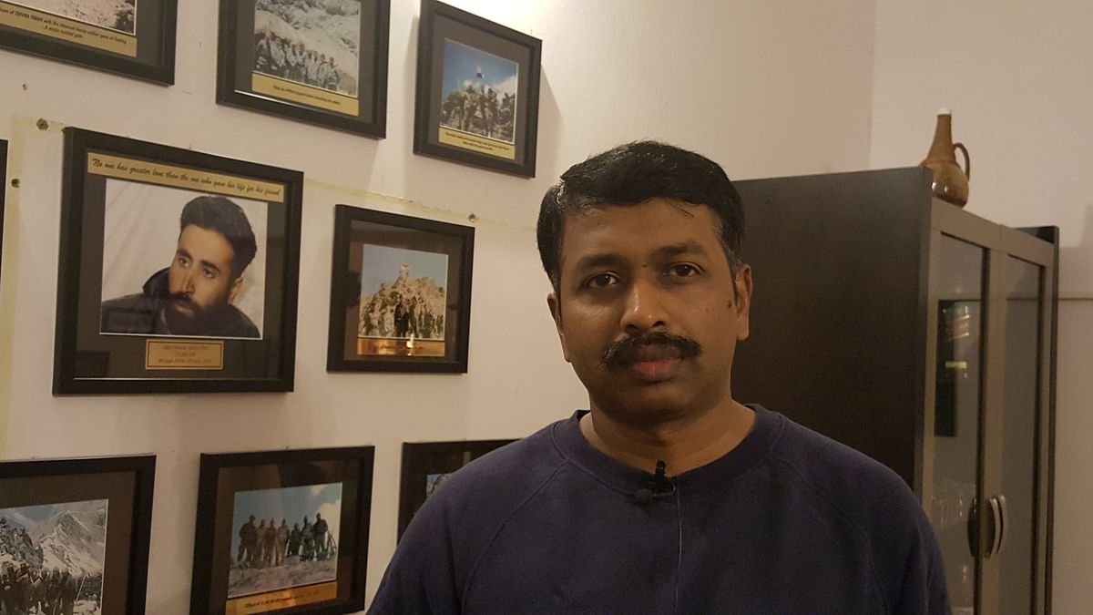 Retd Captain Naveen Nagappa at his residence where he has pictures from Operation Vijay adorning the wall. (Photo: The Quint)