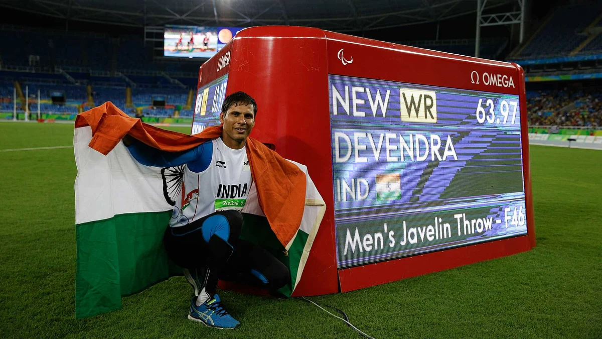 India’s Devendra Jhajharia poses for the pictures next to the scoreboard that shows his world record in the men’s javelin throw F46 athletics event at the Paralympic Games. (Photo: AP)